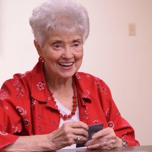 Smiling senior woman playing cards in senior living complex