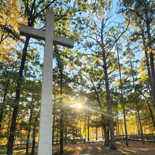 LARGE CROSS IN WOODED SETTING WITH SUN RAYS SHINING