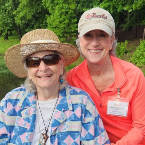 TWO SENIOR LADIES POSING FOR PHOTO IN A GREEN NATURAL SETTING