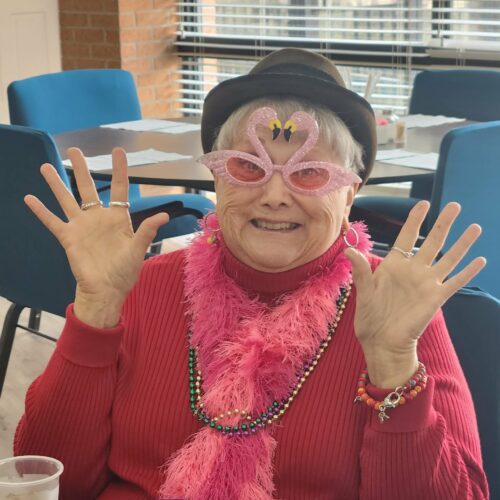 A senior independent living resident smiling and celebrating at a Valentine's Day party.