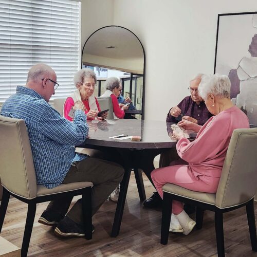Four senior residents smiling and enjoying a game of bridge at Good Shepherd Community.