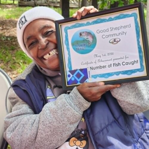 Resident smiling with award won for catching the most fish.